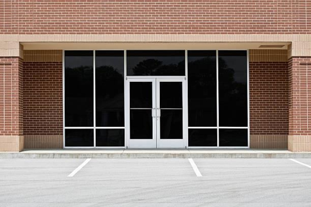 Exterior view of a commercial building with dark-tinted windows and a glass door, offering no visibility into the interior. The tint provides enhanced privacy and security while maintaining a clean, professional storefront appearance.