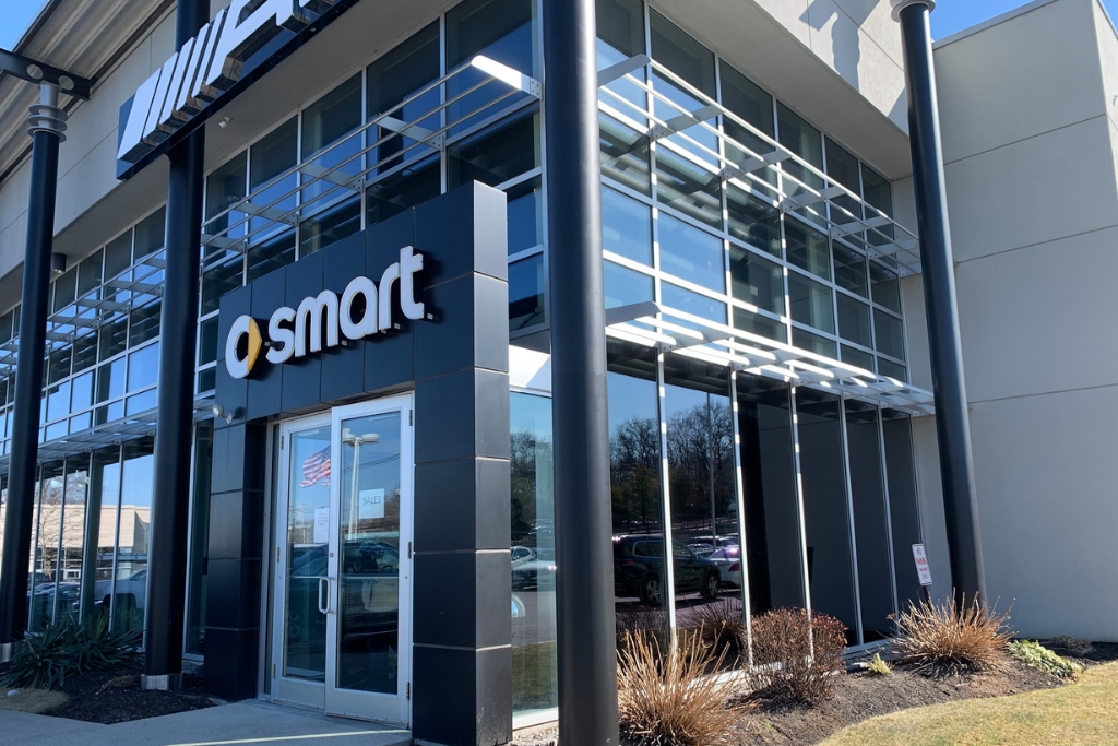 Modern commercial building with large glass windows and a sleek black entrance sign displaying the “smart” brand logo. The tinted and reflective windows enhance the building’s aesthetics while supporting branding and energy efficiency.