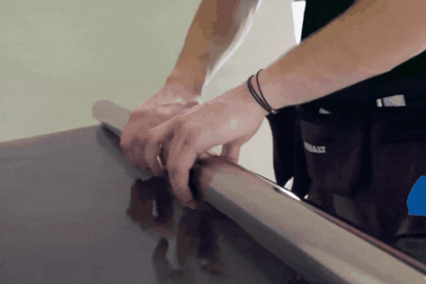 Close-up of a professional installer unrolling a sheet of window tint film onto glass during a commercial window tinting project. This detailed process highlights the precision and care involved in applying high-performance window films.