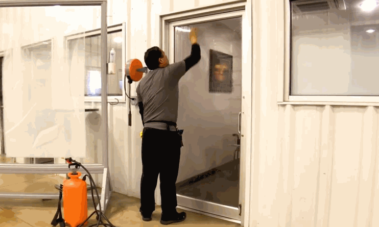 Technician installing Security Window Film on a commercial glass door inside a business facility to reinforce glass and improve safety and security.
