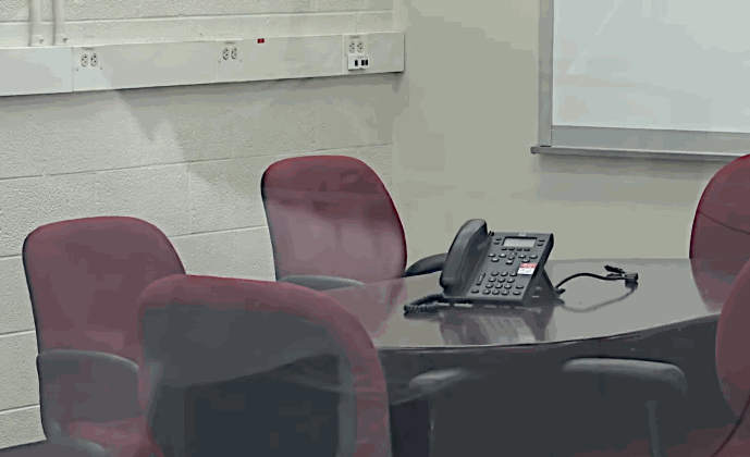 Empty business conference room with chairs and a phone on the table highlighting commercial interiors where Security Window Film can add protection to exterior facing windows and doors.