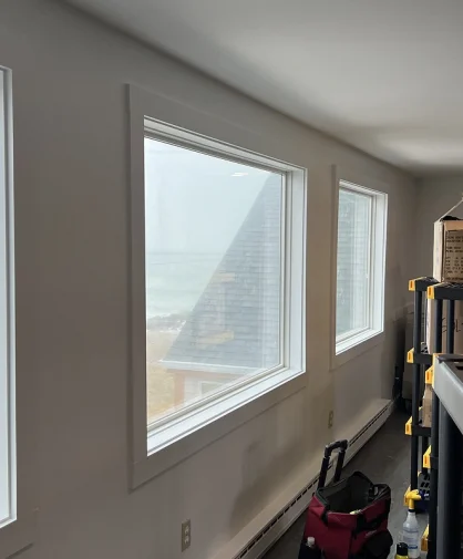 A person cleaning windows inside a room with a beach view, showing clear and clean windows.